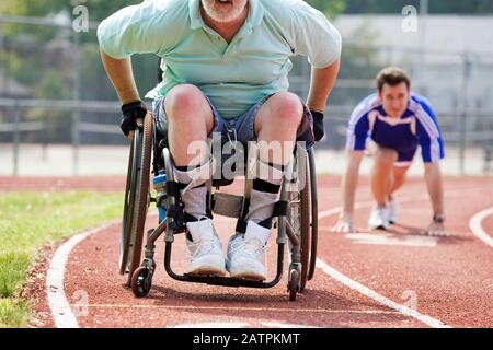 Jeune homme courir avec un homme handicapé sur un hippodrome. Banque D'Images