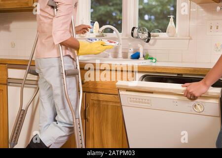 Vue en coupe d'une femme d'âge moyen debout dans le cuisine et vaisselle Banque D'Images