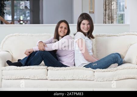 Portrait de deux adolescentes assises sur un canapé à accueil Banque D'Images