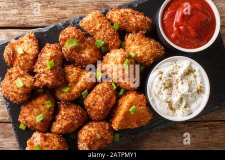 Nuggets croustillants de poulet à la noix de coco servis avec ketchup et mayonnaise sur une planche en ardoise sur une table. Vue de dessus horizontale Banque D'Images