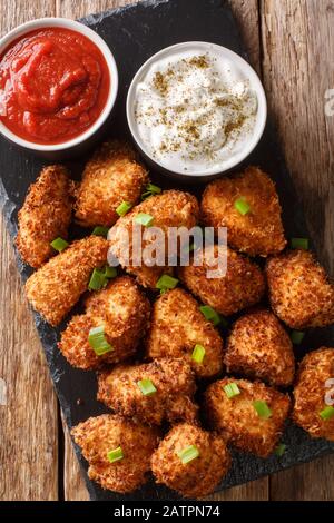 Poulet croustillant à la noix de coco avec deux sauces rapprochés sur une planche en ardoise sur la table. Vue verticale du dessus Banque D'Images