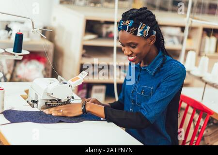 Jeune ouvrier africain du textile à coudre sur la chaîne de production. Femme couturière travaillant avec machine à coudre Banque D'Images
