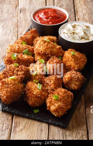 Nuggets croustillants de poulet à la noix de coco servis avec ketchup et mayonnaise sur une planche en ardoise sur une table. Vertical Banque D'Images