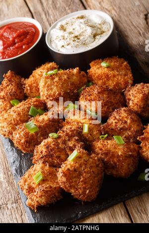 Poulet pané à la noix de coco frite avec deux sauces sur une planche en ardoise sur une table. Verticale Banque D'Images