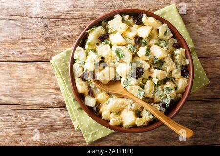Servir une salade de pommes de terre avec du yaourt, des herbes, des épices et des olives séchées dans un bol sur la table. Vue de dessus horizontale Banque D'Images