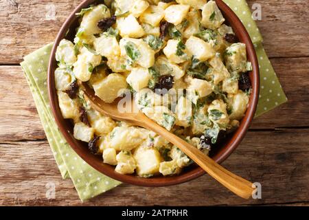 Salade de pommes de terre de cuisine marocaine avec yaourt, herbes, épices et olives séchées dans un bol sur la table. Vue de dessus horizontale Banque D'Images
