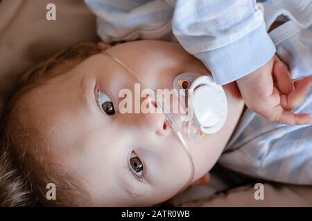 Bébé garçon avec la paralysie cérébrale obtient de l'oxygène par des broches nasales pour assurer la saturation en oxygène. Cathéter nasal dans un enfant patient à l'hôpital. Banque D'Images