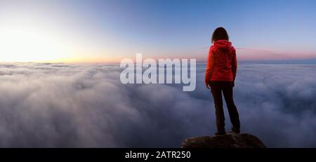 Une fille aventureuse sur un pic des montagnes Rocheuses au-dessus des nuages en profitant de la vue magnifique sur le coucher De soleil Ou le lever du soleil. Positionnement De L'Image Aventure, T Banque D'Images