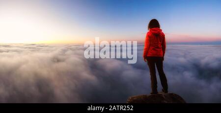 Une fille aventureuse sur un pic des montagnes Rocheuses au-dessus des nuages en profitant de la vue magnifique sur le coucher De soleil Ou le lever du soleil. Positionnement De L'Image Aventure, T Banque D'Images