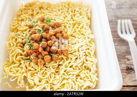 bol de soupe de ramen. Tom Yam kun nouilles instantanées avec de la viande séchée et des additifs végétaux sur une table en bois. Soupe rapide préparée à chaud dans un emballage jetable Banque D'Images