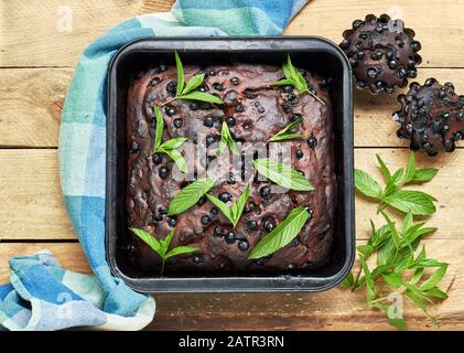 Gâteau sans oeufs au chocolat avec bleuets et menthe décoré juste cuit sur fond rustique en bois, plat, de dessus vue de dessus, ferme, espace de copie, Banque D'Images