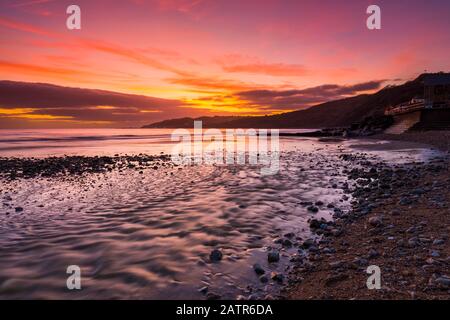 Charmouth, Dorset, Royaume-Uni. 4 février 2020. Météo britannique. Un spectaculaire coucher de soleil sur la plage de Charmouth à Dorset en regardant vers l'ouest le long de la côte vers Lyme Regis. Crédit Photo : Graham Hunt/Alay Live News Banque D'Images