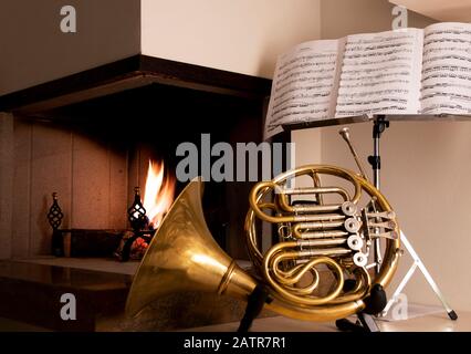 Musique ouverte sur un stand avec avertisseur en laiton devant un feu brûlant dans une cheminée avec foyer avec foyer à l'instrument Banque D'Images