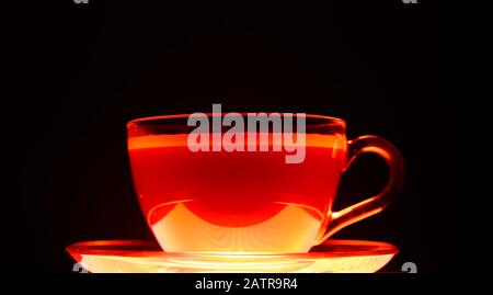 Gros plan d'une tasse de café marron transparente isolée illuminée en rouge clair et noir Banque D'Images