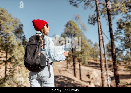 Jeune femme vêtue de marche décontractée avec un sac à dos dans la forêt très dans les montagnes sur les roches volcaniques Banque D'Images