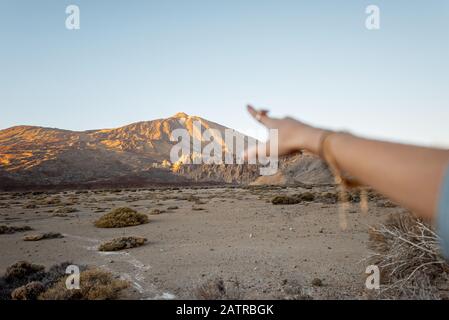 Femme pointant à la main sur la montagne volcanique pendant un coucher de soleil, gros plan sur la main Banque D'Images