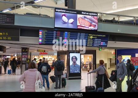 Intérieur de l'aéroport de Gatwick terminal Sud - passagers regardant le départ, aéroport de Londres Gatwick, Royaume-Uni Banque D'Images