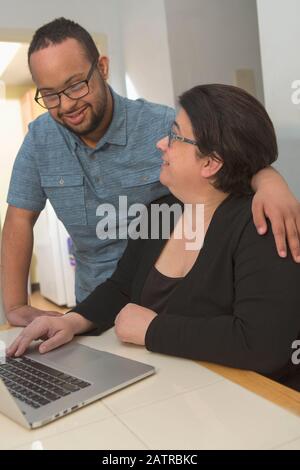 Mère et jeune fils adulte à la maison utilisant un ordinateur portable Banque D'Images