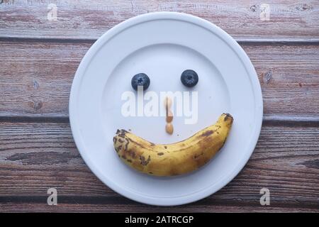 vue de dessus du visage drôle avec des fruits sur plaque Banque D'Images