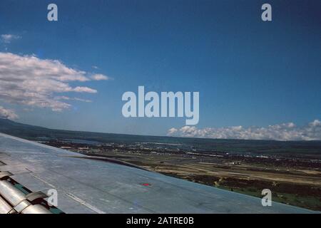 Photographie vernaculaire prise sur une transparence de film analogique de 35 mm, vue de paysage de la fenêtre d'avion avec aile visible, 1970. Les principaux sujets/objets détectés sont le ciel, la mer et le véhicule. () Banque D'Images