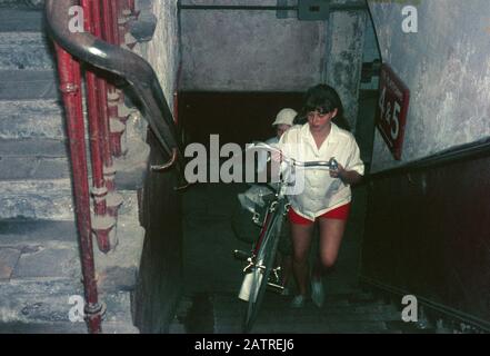 Photographie vernaculaire prise sur un film analogique de 35 mm transparent, considérée comme représentant des personnes transportant des vélos en haut d'un escalier, 1970. () Banque D'Images