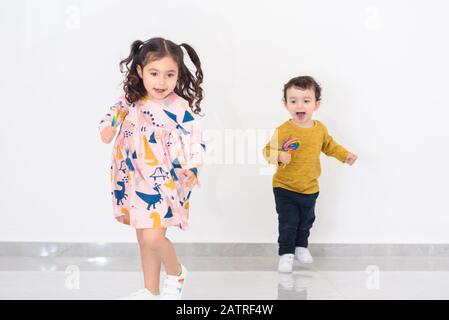 Deux Jeunes Enfants Qui Tournent Vers L'Appareil Photo À La Maison. Mise au point douce pour montrer le mouvement. Banque D'Images