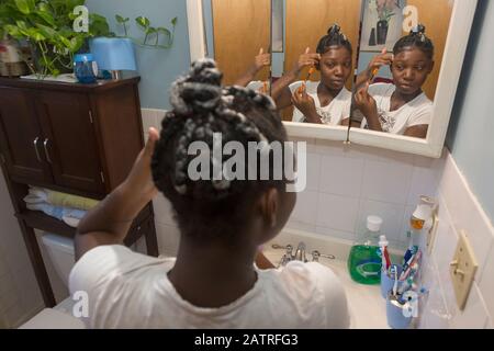 Adolescent souffrant du trouble bipolaire faisant ses cheveux Banque D'Images