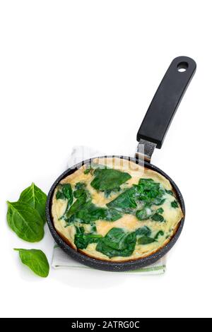 Omelette aux épinards dans une petite poêle isolée sur blanc Banque D'Images