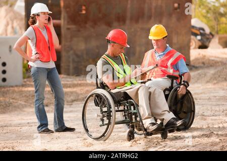 Chantier de construction avec des hommes en fauteuil roulant et une femme qui parle sur le téléphone Banque D'Images