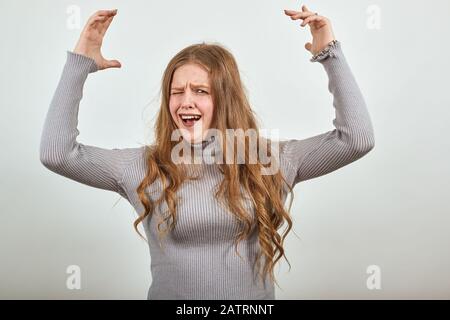 une femme en pull gris soulève joyeusement ses mains cries avec plaisir Banque D'Images