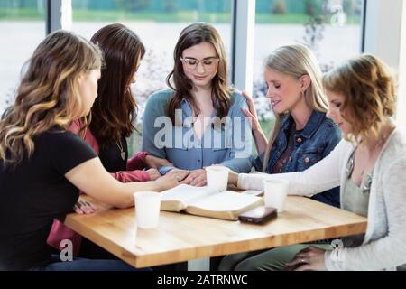 Un groupe de femmes se réunissaient pour prier une des femmes après une étude de la Bible dans un café d'une église; Edmonton, Alberta, Canada Banque D'Images