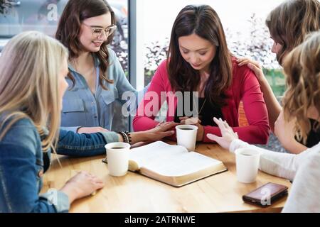 Un groupe de femmes se réunissaient pour prier une des femmes après une étude de la Bible dans un café d'une église; Edmonton, Alberta, Canada Banque D'Images