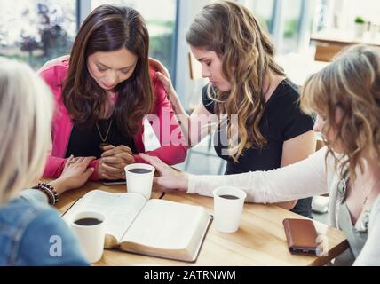 Un groupe de femmes se réunissaient pour prier une des femmes après une étude de la Bible dans un café d'une église; Edmonton, Alberta, Canada Banque D'Images