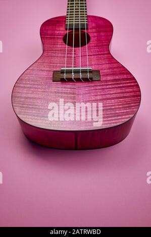 partie de l'ukulele rose sur fond rose avec copyspace, photo couleur verticale Banque D'Images