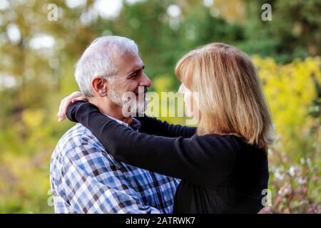 Un couple d'âge mûr se faisant un plaisir de se regarder ensemble dans un parc de la ville lors d'une chaude soirée d'automne; St. Albert, Alberta, Canada Banque D'Images