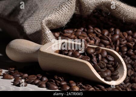 Grains de café dans une pelle avec sac de Hesse sur bois Banque D'Images