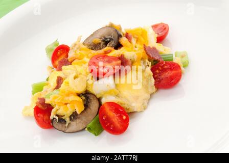 Petit déjeuner sain composé d'œufs brouillés, de tomates de raisin, de champignons tranchés, de bacon de dinde, de cheddar et d'oignons de printemps. Banque D'Images