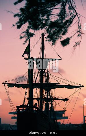 Silhouette d'un bateau caravel espagnol du XVe siècle encadré par des branches d'arbres tout en amarré dans le port Banque D'Images