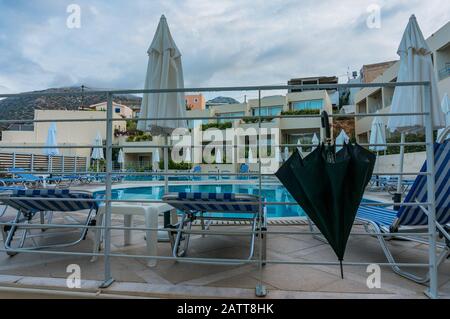 Bali, Crète, Grèce - 08.10.2019: Après la pluie près de la piscine dans le complexe. Parasols pliés et un grand parapluie noir. Banque D'Images