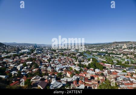 Vue panoramique à grand angle de Tbilissi depuis la colline de Sololaki, avec la rivière Kura traversant le centre-ville et les montagnes en arrière-plan (Géorgie) Banque D'Images