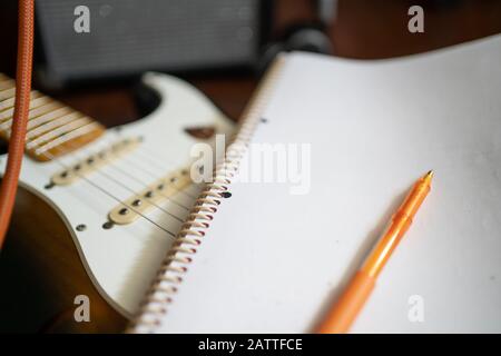 Écriture de chansons. Bloc-notes et stylo avec guitare électrique Banque D'Images