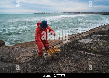 Gros plan d'un pêcheur mettant sur l'appât avec la boîte d'équipement de pêche. Concept de pêche et de sport. Banque D'Images