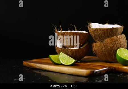 Noix de coco naturelle saine et nutritive avec une vaste gamme d'avantages et d'utilisations diététiques et cosmétiques, présentées ici avec des moitiés de noix de coco et des limes tacheées Banque D'Images