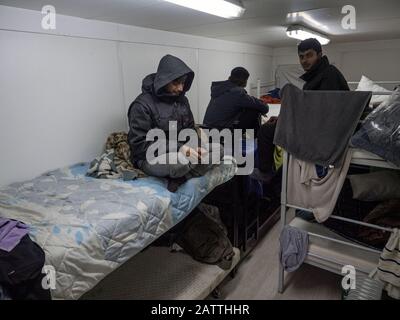 11 décembre 2019, Sarajevo, Bosnie-Herzégovine: Les hommes dans un logement pour conteneurs au camp de réfugiés d'Usivak près de Sarajevo.En Bosnie-Herzégovine, environ 8 000 réfugiés et migrants essaient de trouver un moyen de traverser la frontière avec la Croatie et d'aller plus loin vers les pays d'Europe occidentale. Certains d'entre eux vivent dans des camps de réfugiés surpeuplés, certains d'entre eux sont squatés dans des bâtiments abandonnés ou dorment simplement dans les rues. Beaucoup d'entre eux rapportent que s'ils sont pris à la frontière par la police croate, ils sont battus, leur argent comptant, les smartphones et les objets de valeur sont volés, les vestes et les chaussures sont brûlés et ils Banque D'Images