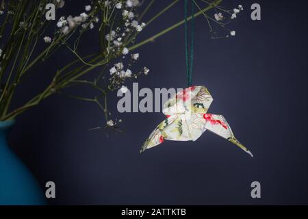 Un colibri origami accroché à partir de Gypsophila séchée dans un vase. Banque D'Images