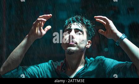 Portrait d'un jeune homme sortant sous la pluie dans les rues de la ville. Concept De Liberté. Banque D'Images