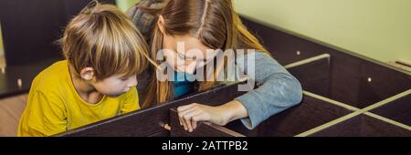 Mère et fils assemblant des meubles. Garçon aidant sa mère à la maison. BANNIÈRE de concept Happy Family, FORMAT LONG Banque D'Images