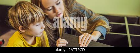 Mère et fils assemblant des meubles. Garçon aidant sa mère à la maison. BANNIÈRE de concept Happy Family, FORMAT LONG Banque D'Images