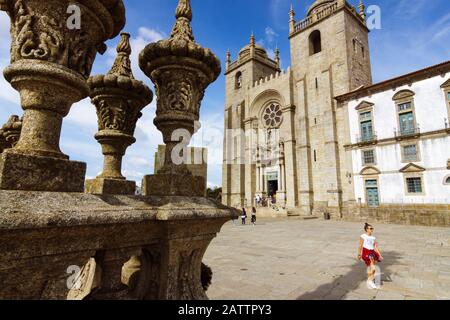 Porto, Portugal : une jeune femme passe devant la cathédrale de Porto, construite au XIIe siècle, avec des modifications baroques et du XXe siècle. Banque D'Images