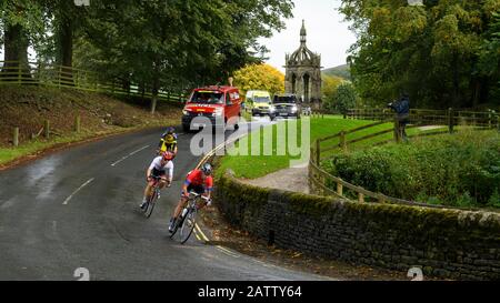 Cyclistes juniors de course sur route masculine sur des vélos, équitation et compétition en course de cycle, véhicules d'équipe suivant - UCI World Championships, Bolton Abbey, GB, Royaume-Uni. Banque D'Images